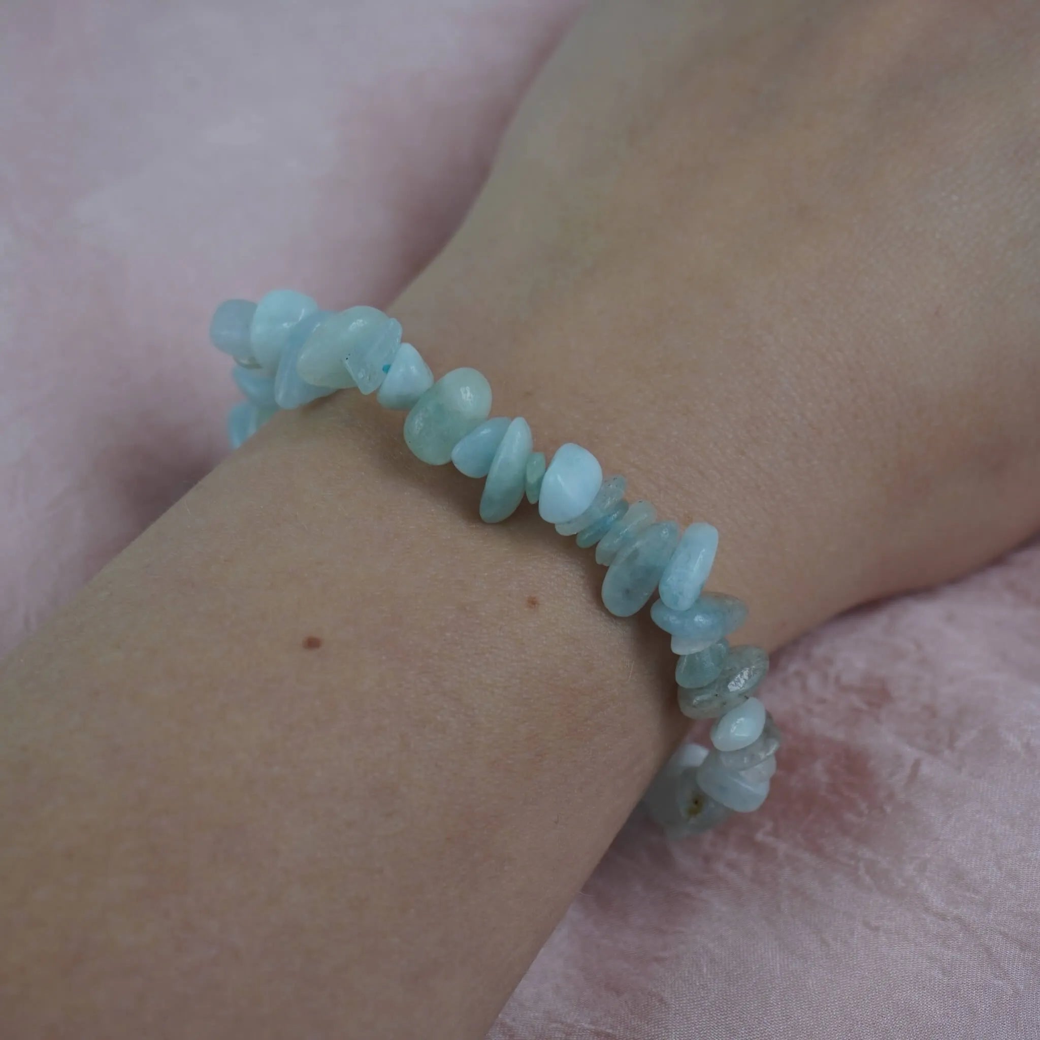 Aquamarin‑Splitterarmband am Handgelenk auf rosa Untergrund