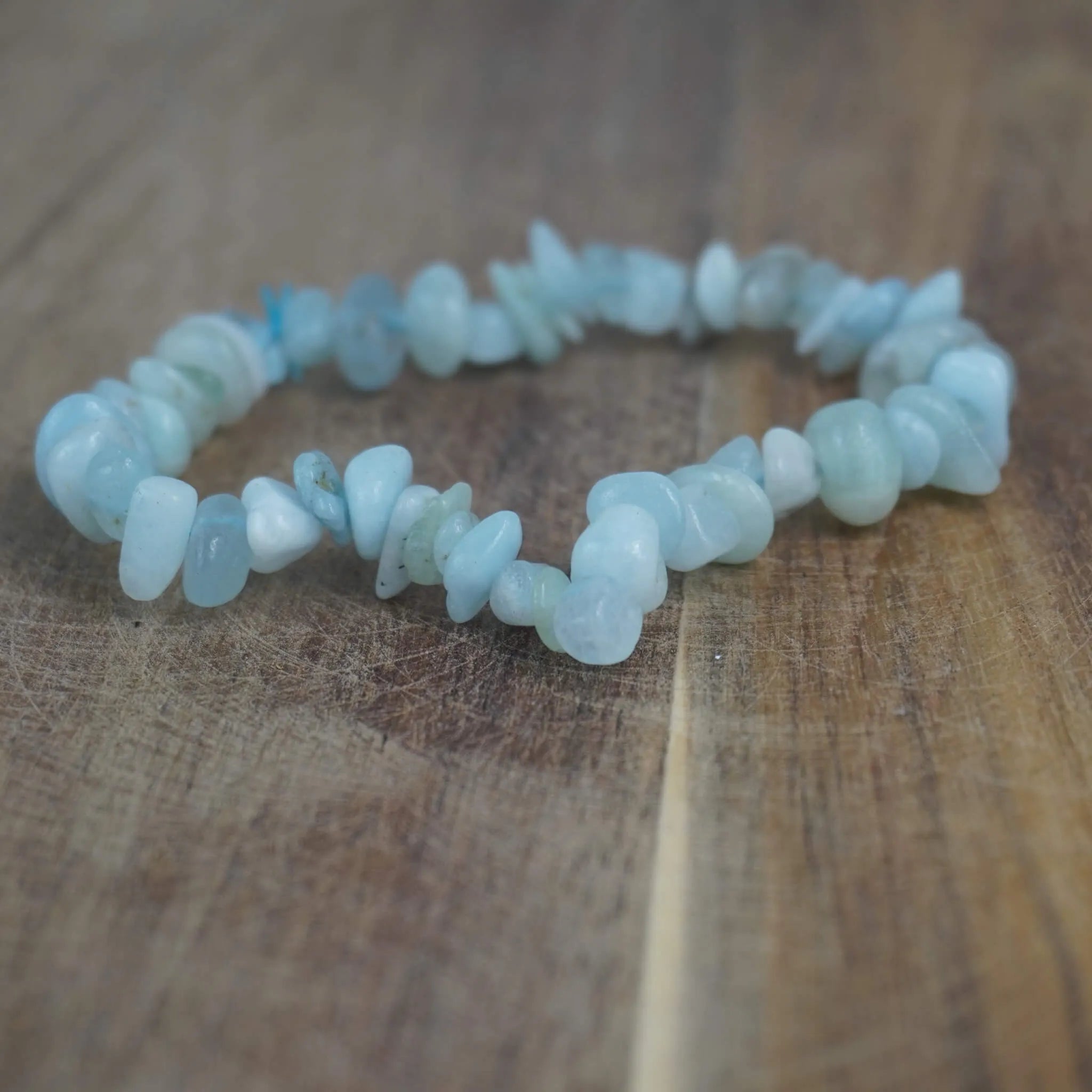 Aquamarin‑Splitterarmband liegt auf rustikaler Holzoberfläche