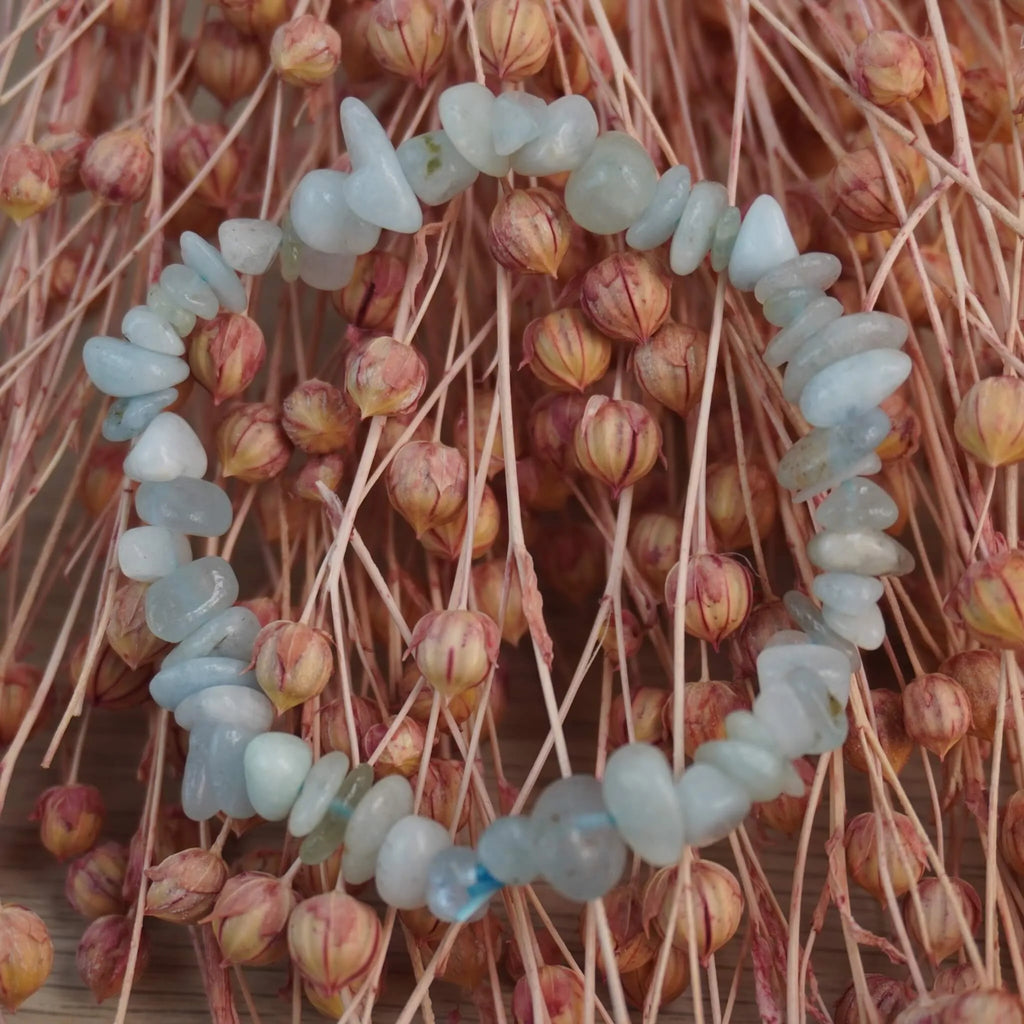 Aquamarin‑Splitterarmband vor rosafarbenen Trockenblumen