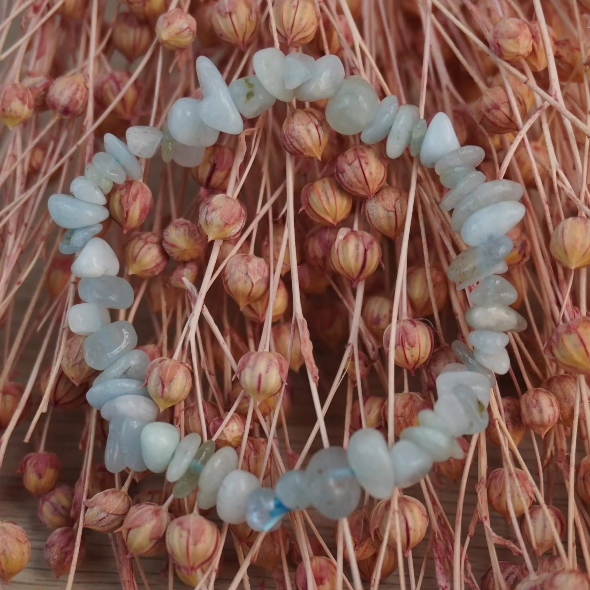 Aquamarin‑Splitterarmband vor rosafarbenen Trockenblumen