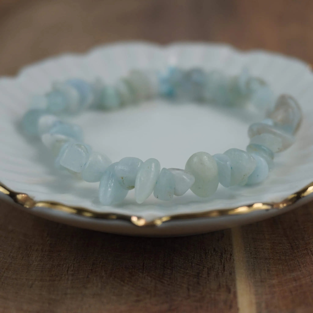 Aquamarin‑Splitterarmband auf weißem Teller mit Goldrand