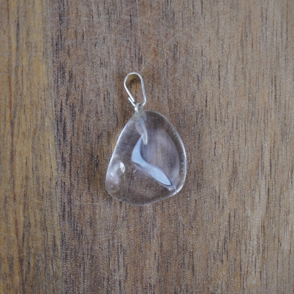 Klarer Bergkristall Trommelstein Kettenanhänger mit silberner Öse vor Holzuntergrund