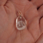 Klarer Bergkristall Trommelstein Kettenanhänger mit Silber Öse in einer Hand liegend
