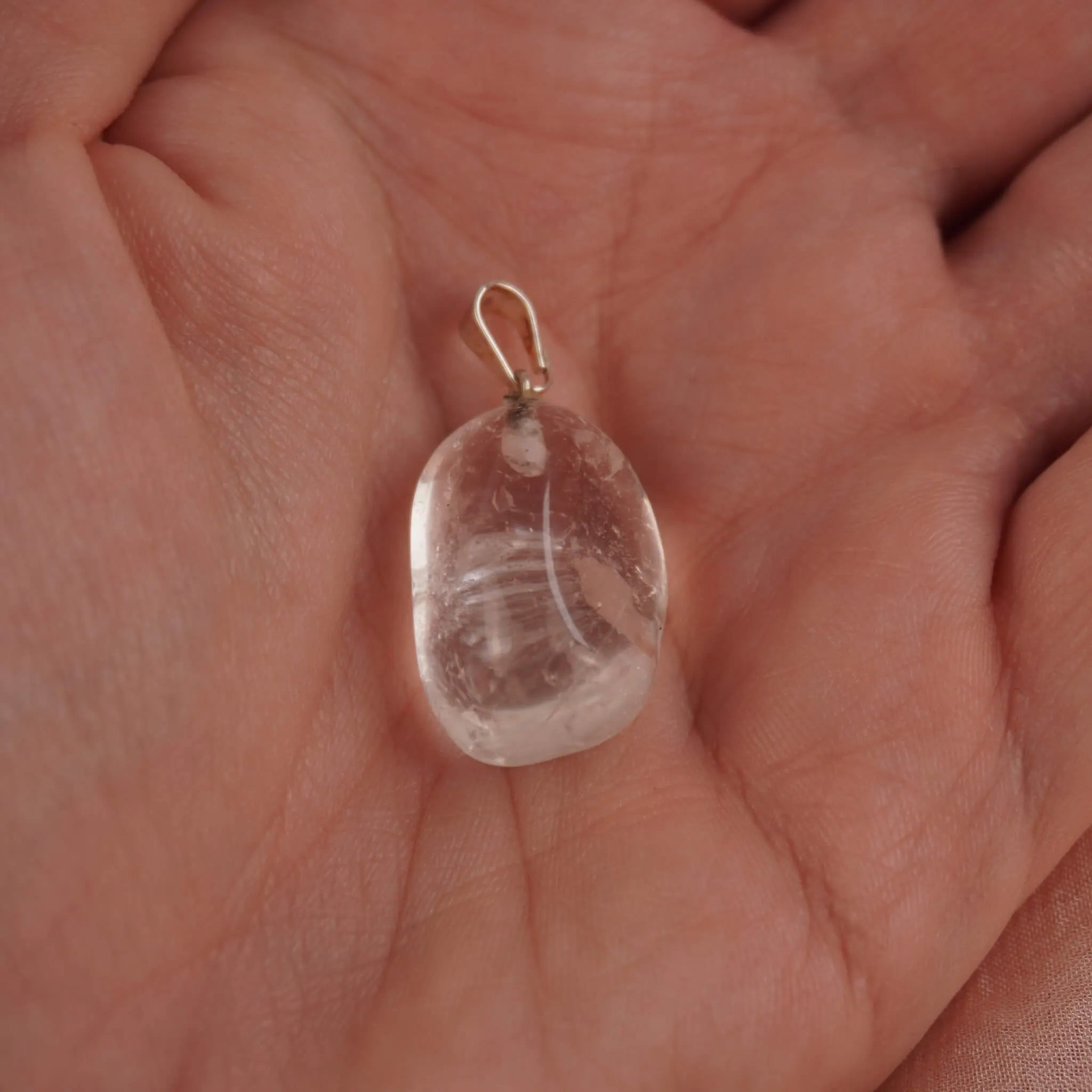 Klarer Bergkristall Trommelstein Kettenanhänger mit Silber Öse in einer Hand liegend