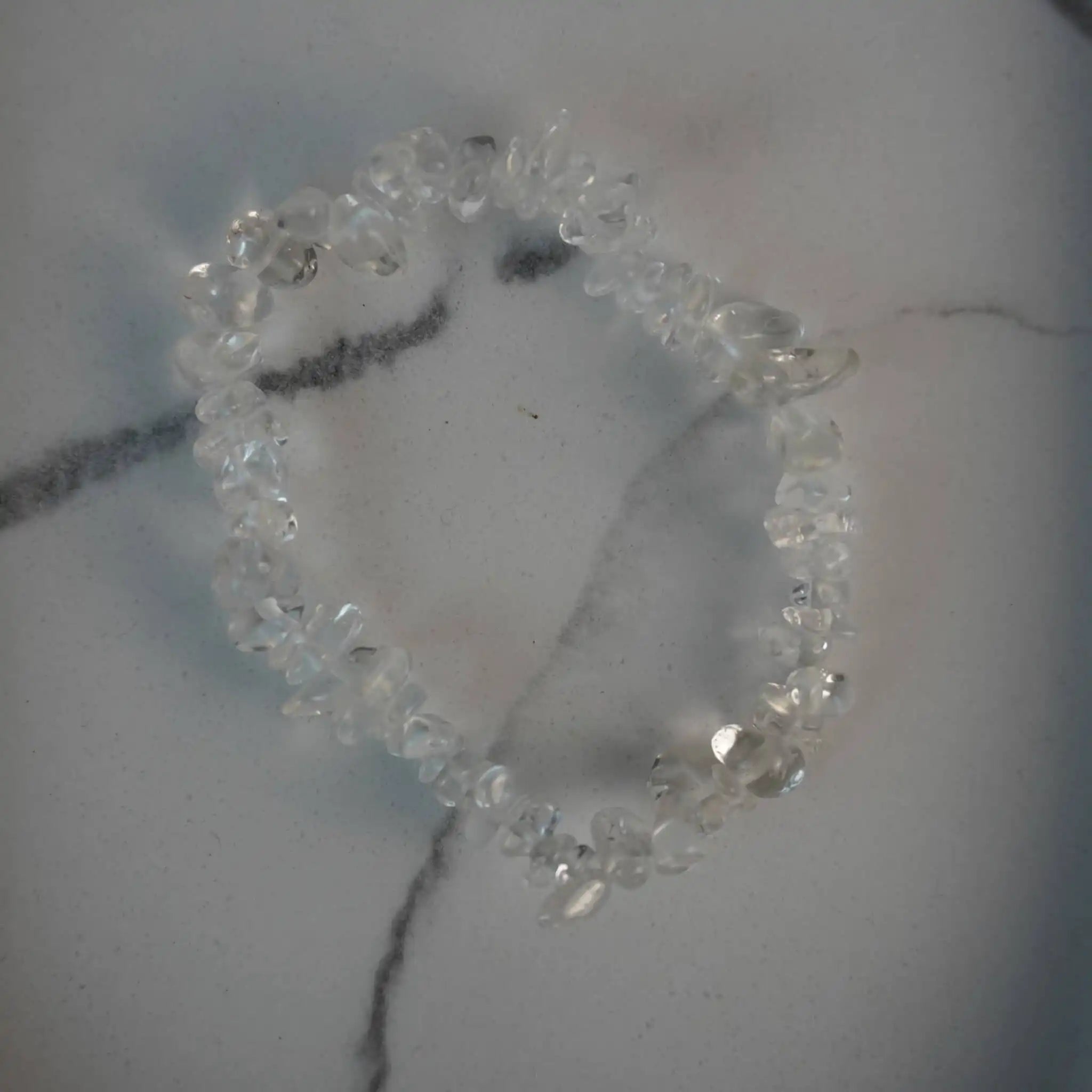 Bergkristall Splitterarmband mit transparenten Edelsteinen auf weißer Marmorfläche