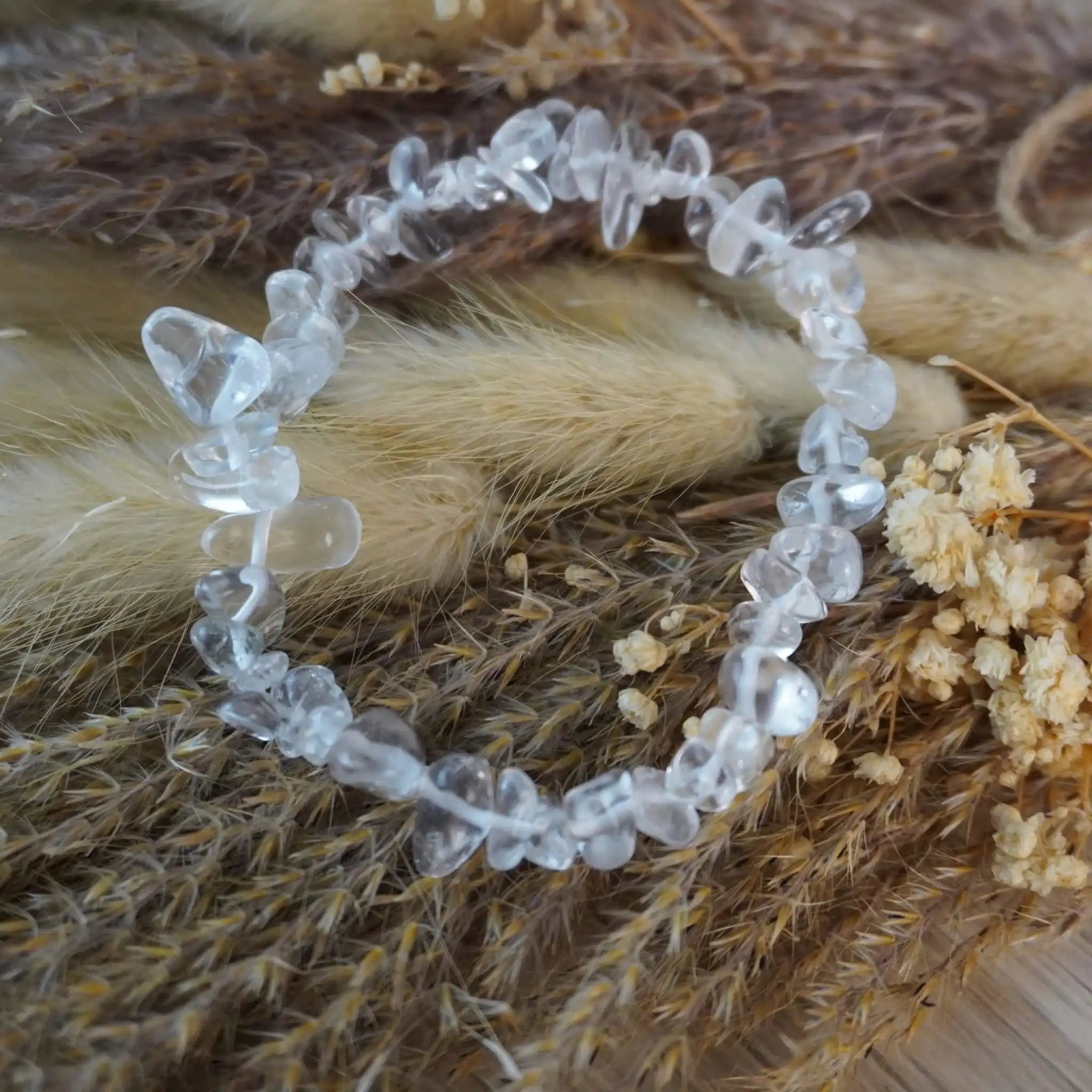Bergkristall Splitterarmband mit klaren Steinen auf naturfarbenen Trockenpflanzen dekoriert