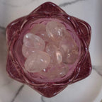 Mehrere Bergkristall Trommelsteine in einer rosa Glasschale