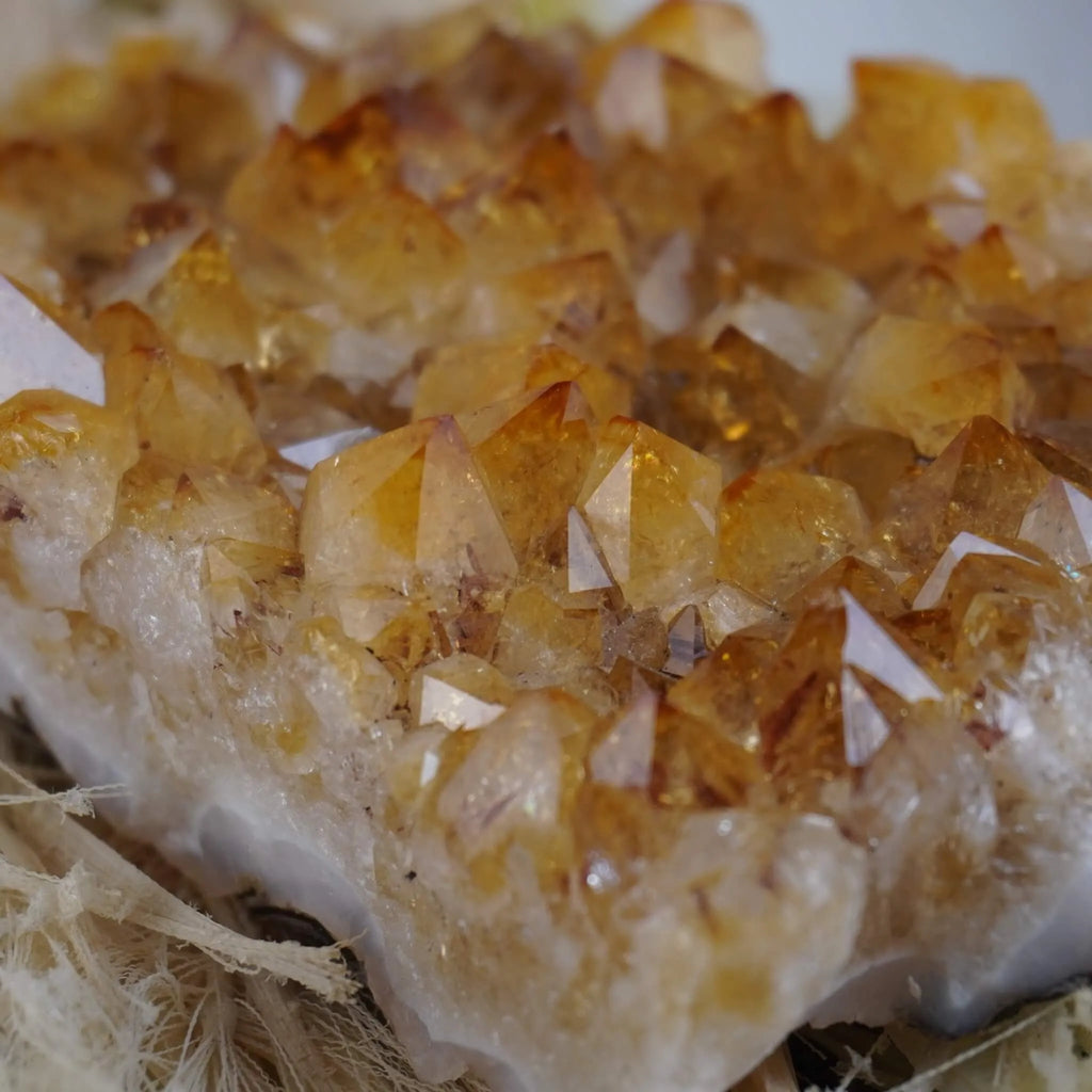 Goldfarbenes Citrin Cluster mit klaren Spitzen auf hellen Naturfasern