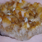 Nahaufnahme eines Citrin Clusters mit warmen Gelbtönen auf rosafarbenem Stoff