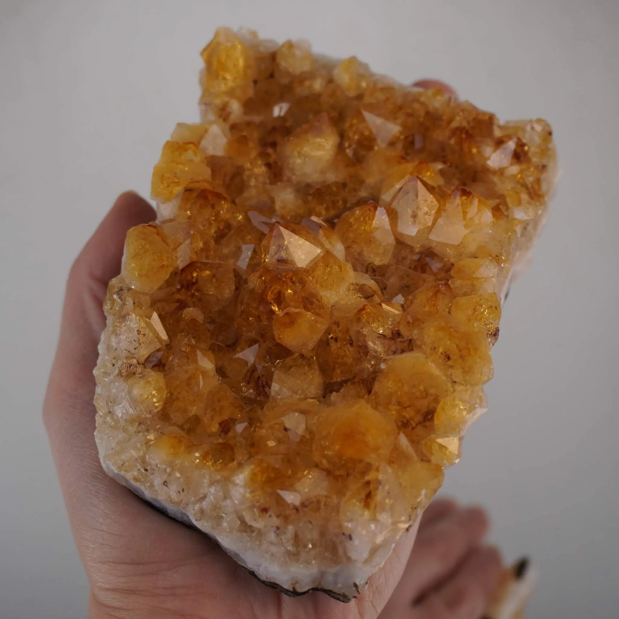 Großes Citrin Cluster mit vielen Kristallen in einer Hand gehalten