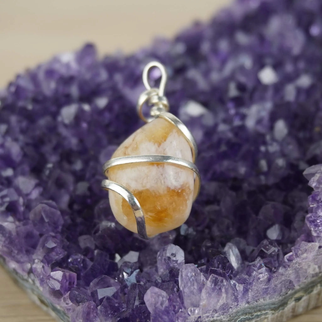 Citrin Kettenanhänger mit silberner Spiralfassung präsentiert auf violetter Amethyst-Druse
