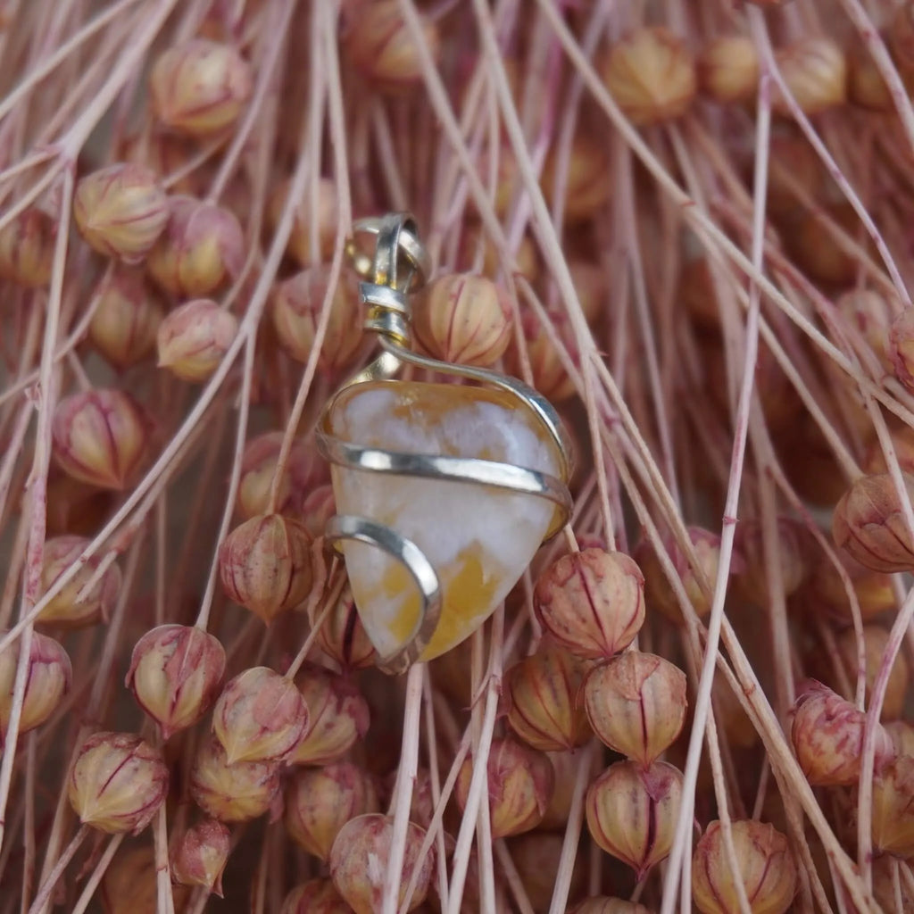 Citrin Kettenanhänger mit Silberfassung vor rosa Trockenblumen arrangiert