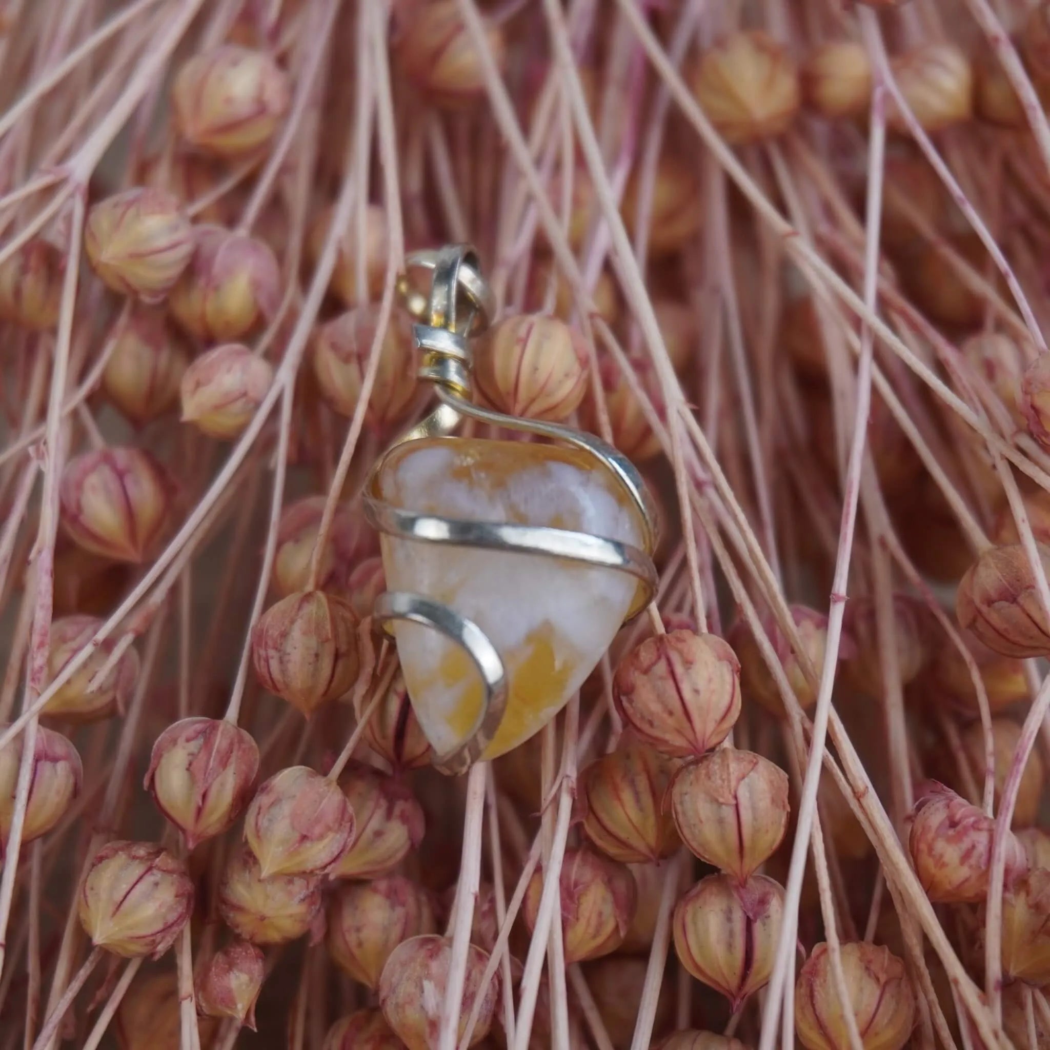 Citrin Kettenanhänger mit Silberfassung vor rosa Trockenblumen arrangiert