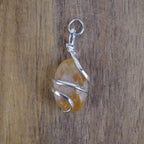 Citrin Kettenanhänger mit Silberfassung vor Holzuntergrund