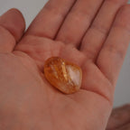 Warmer Citrin Trommelstein in einer geöffneten Hand liegend