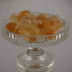 Mehrere Citrin Trommelsteine in verschiedenen Gelbtönen in einem gläsernen Kelch arrangiert