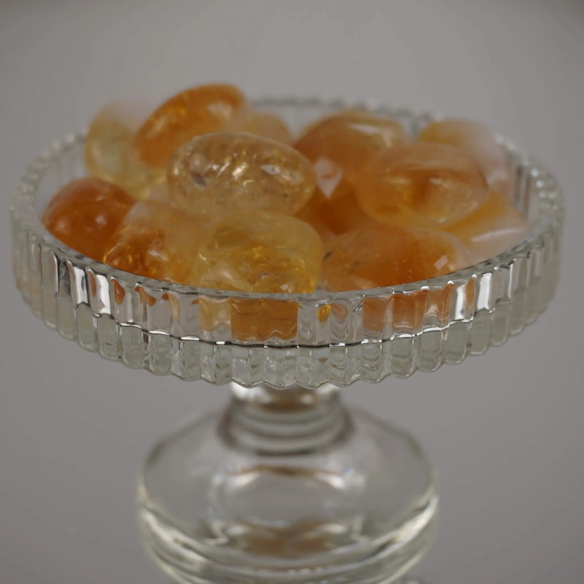 Mehrere Citrin Trommelsteine in verschiedenen Gelbtönen in einem gläsernen Kelch arrangiert