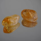 Zwei glänzende Citrin Trommelsteine mit klarer Spiegelung auf glatter Oberfläche