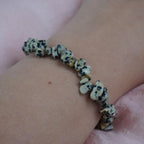 Dalmatiner Jaspis Splitterarmband am Handgelenk auf rosa Untergrund