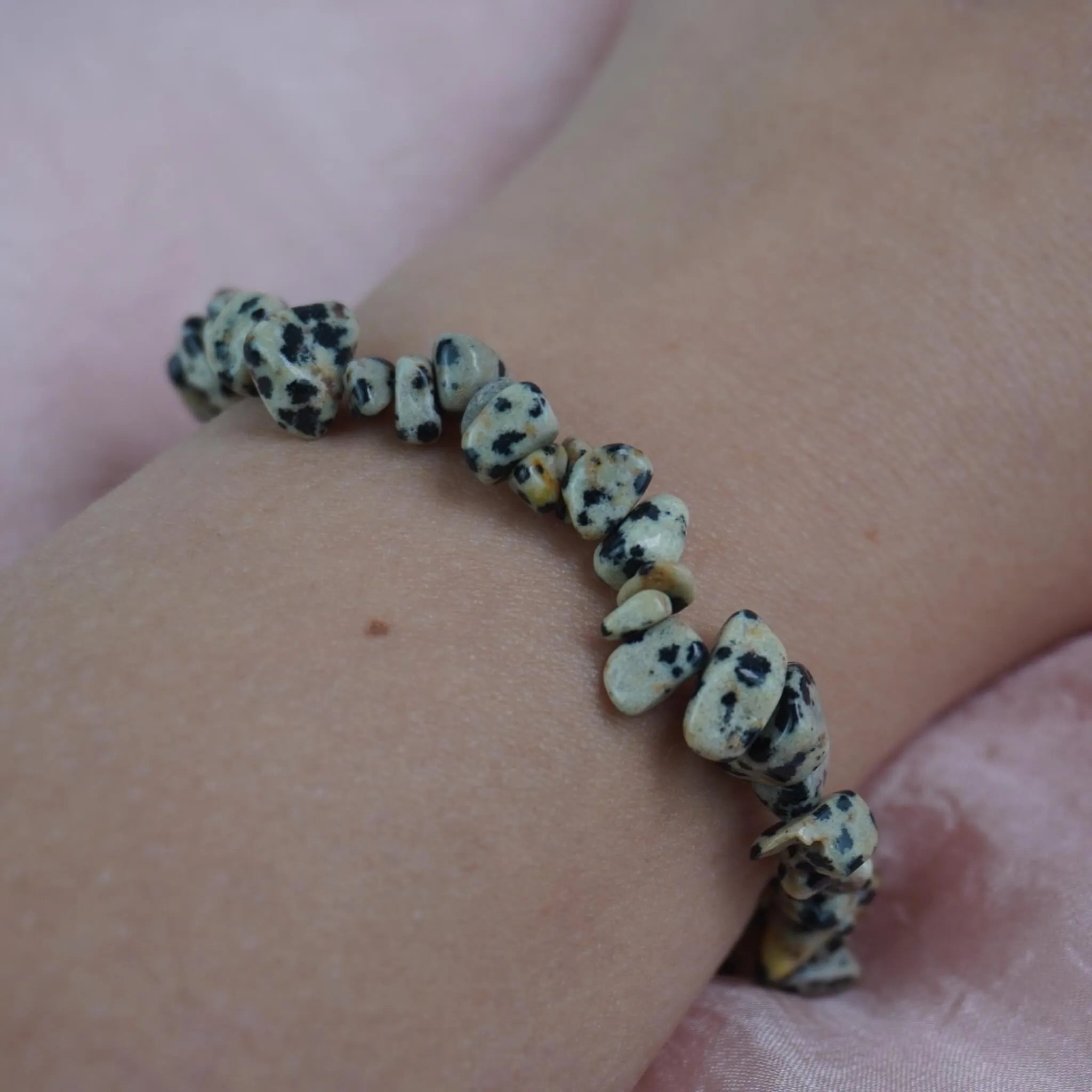 Dalmatiner Jaspis Splitterarmband am Handgelenk auf rosa Untergrund