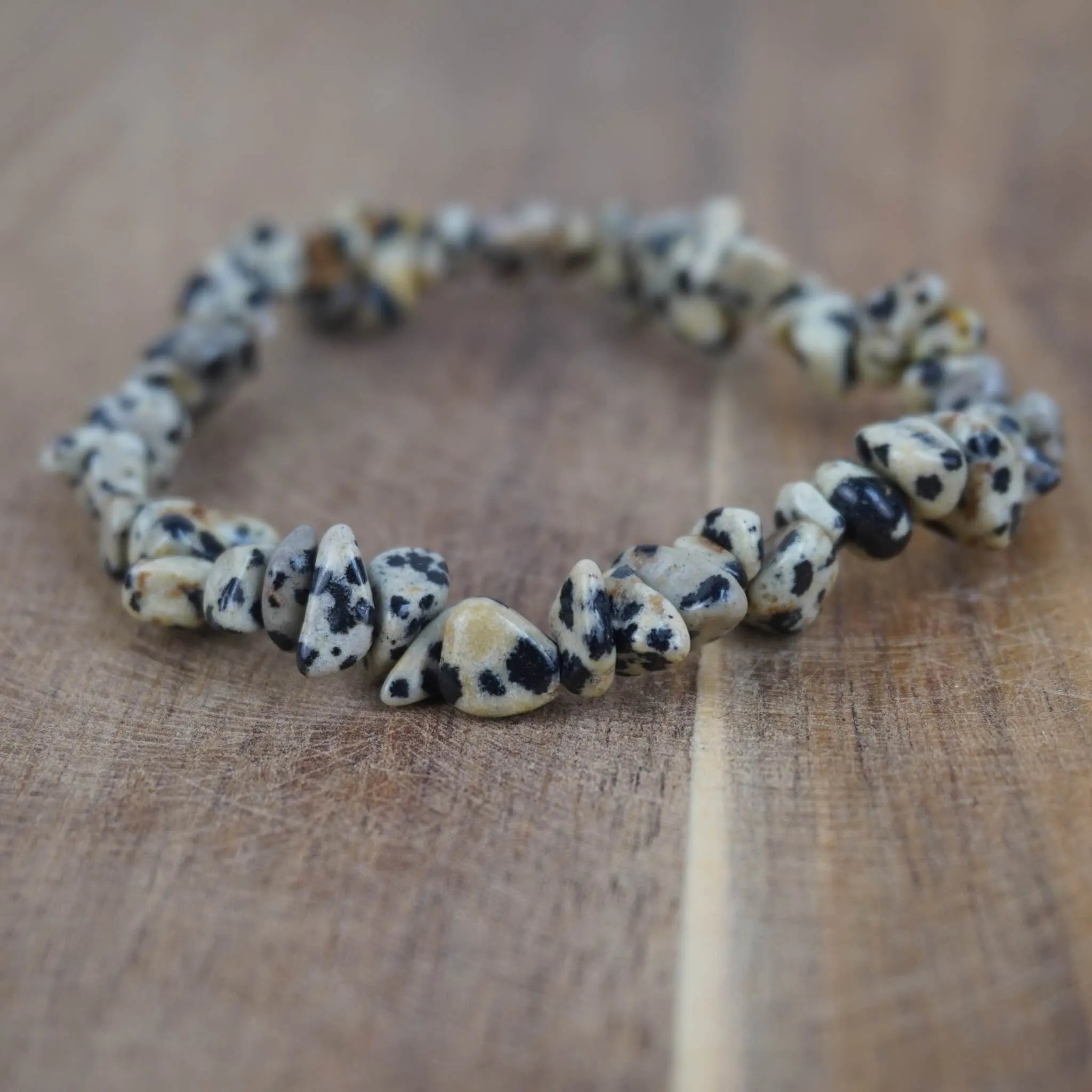 Dalmatiner Jaspis Splitterarmband auf warmer Holzoberfläche, natürlich wirkend