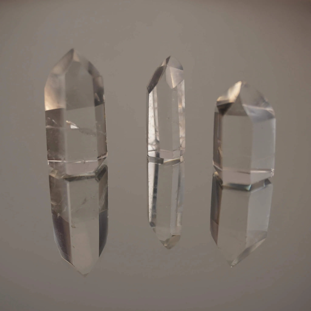 Drei stehende klare Bergkristall Spitzen mit deutlicher Spiegelung auf Glasfläche