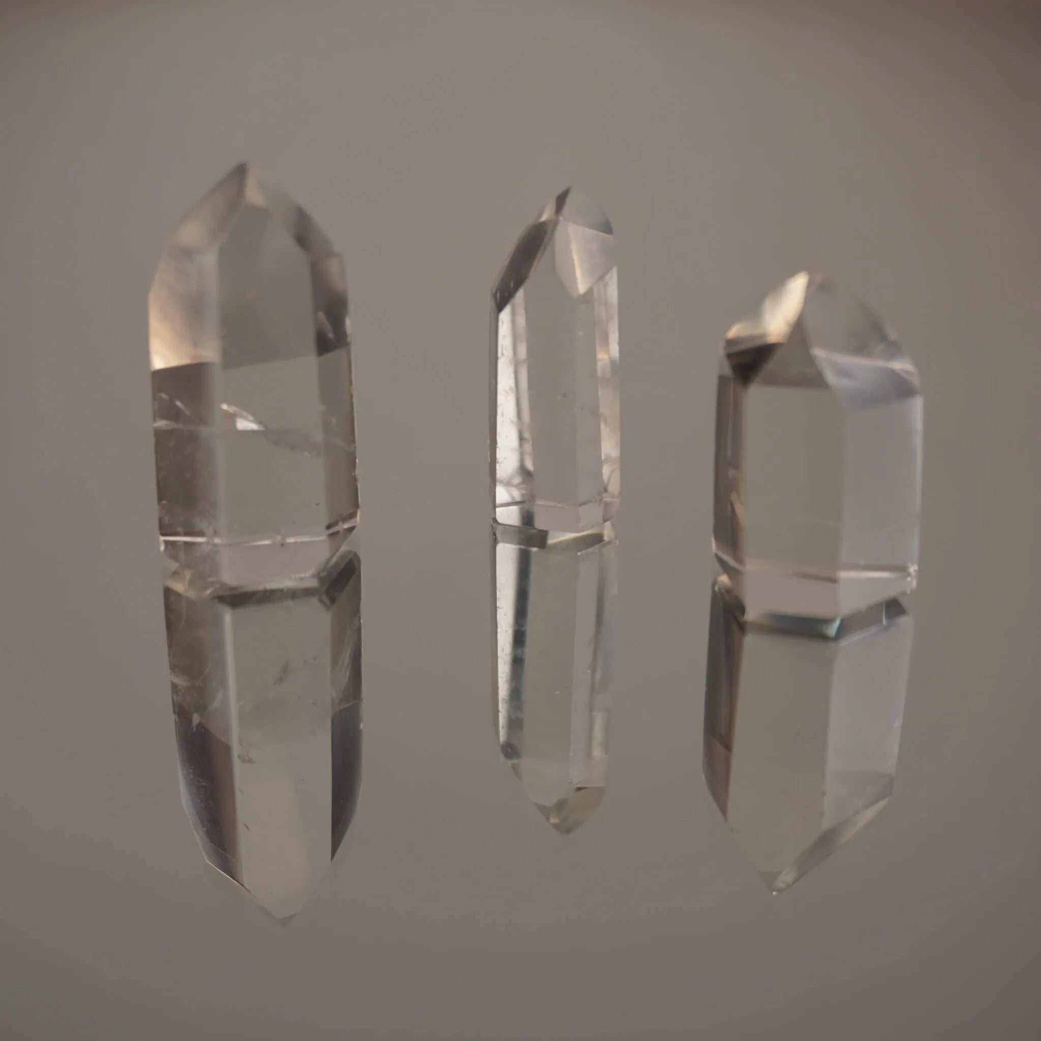 Drei stehende klare Bergkristall Spitzen mit deutlicher Spiegelung auf Glasfläche