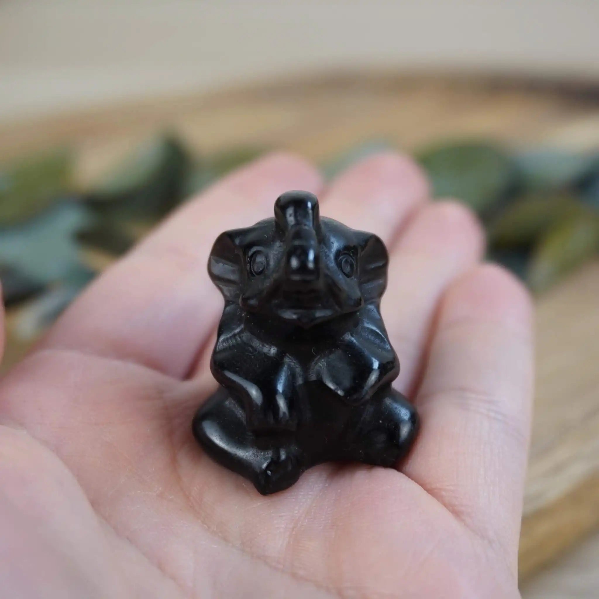 Schwarze Elefantenfigur aus Obsidian in einer Hand