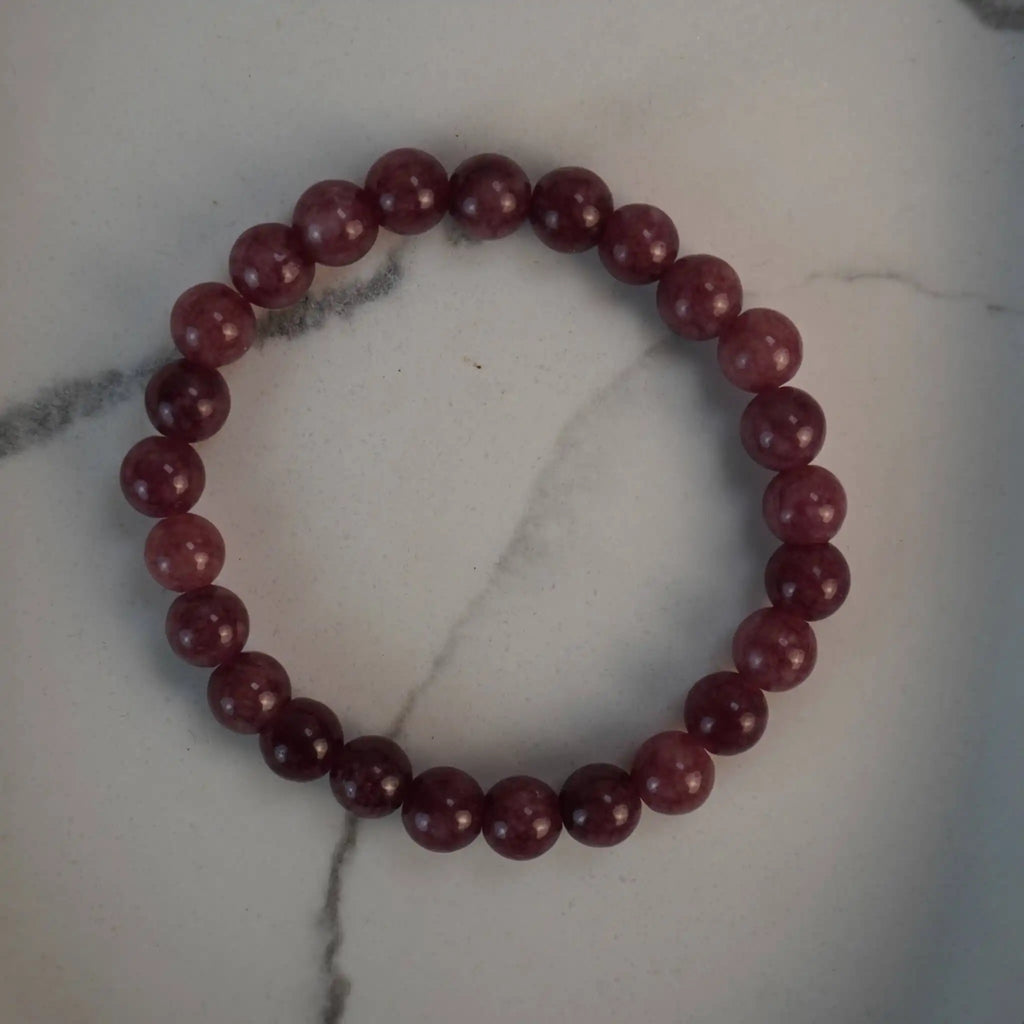 Erdbeerquarz Kugelarmband auf weißem Marmorhintergrund