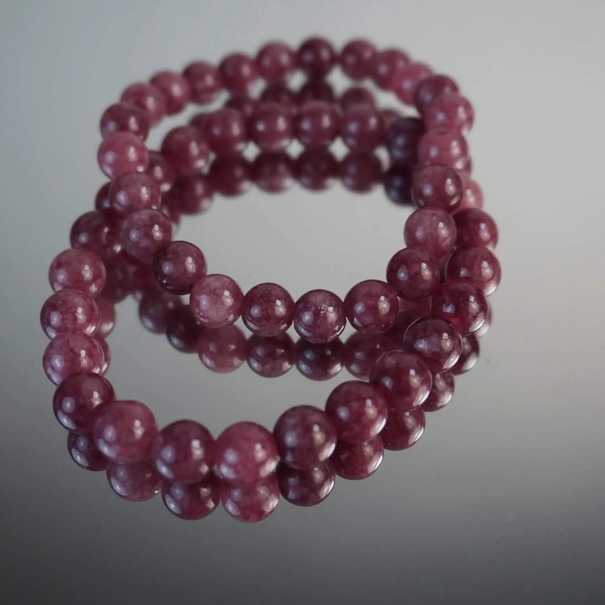 Erdbeerquarz Kugelarmband auf reflektierender Fläche