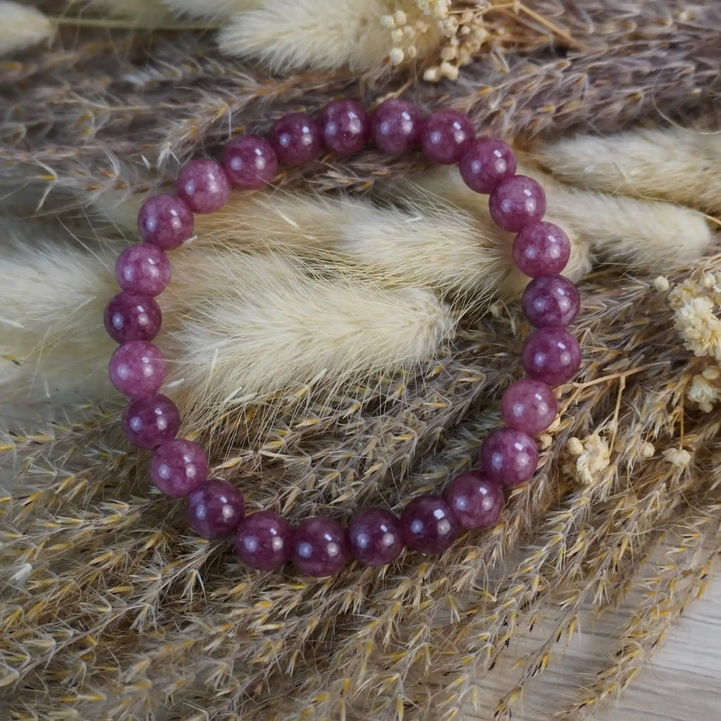 Erdbeerquarz Kugelarmband dekorativ auf Trockenblumen arrangiert