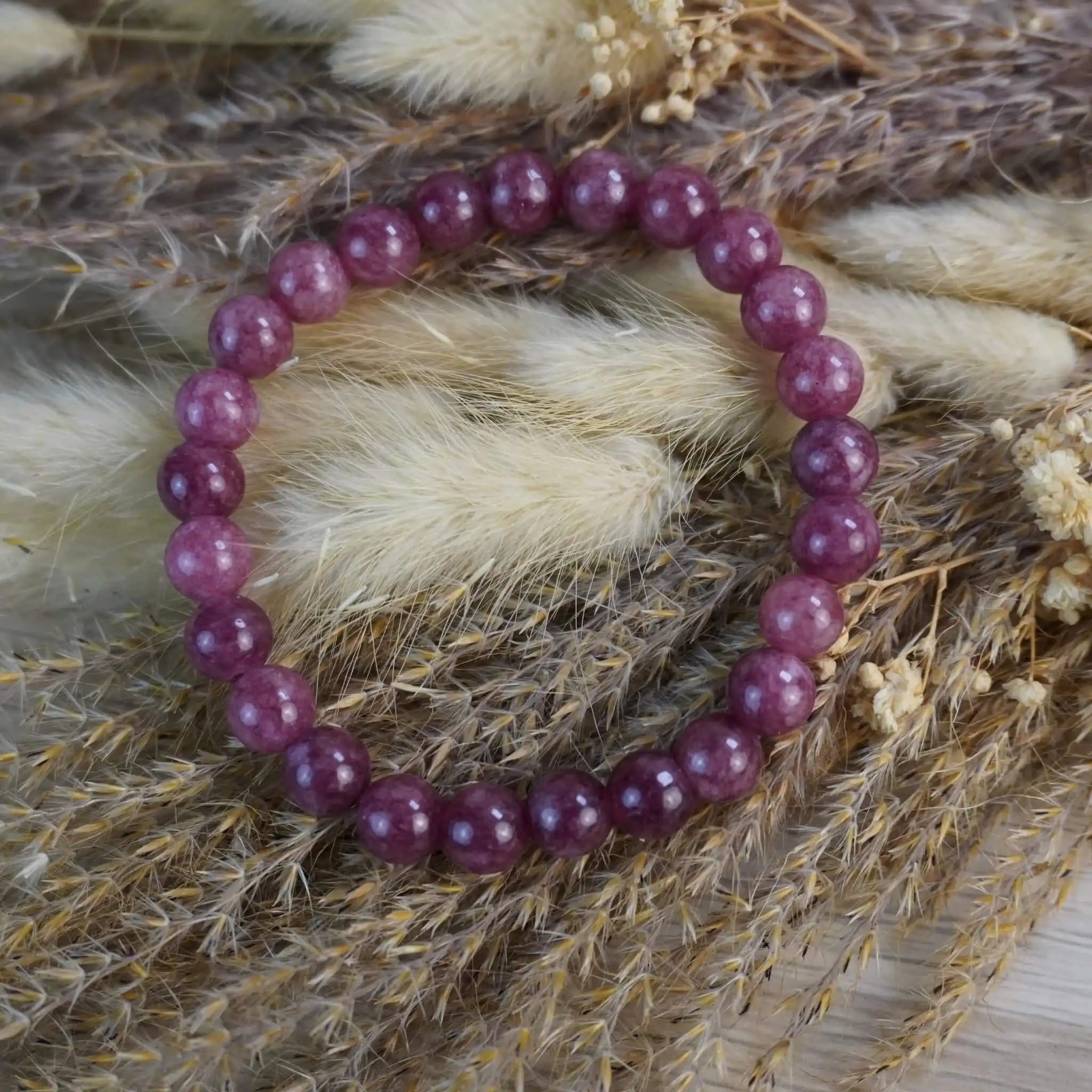 Erdbeerquarz Kugelarmband dekorativ auf Trockenblumen arrangiert