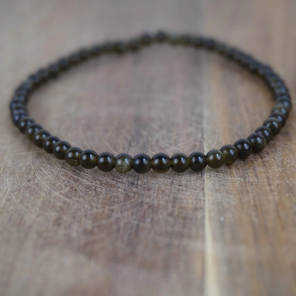 Goldener Obsidian Kugelarmband auf warmer Holzoberfläche im Nahaufnahme-Detail