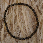 Goldener Obsidian Kugelarmband auf hellem Naturfaserdekor mit sichtbarer Struktur