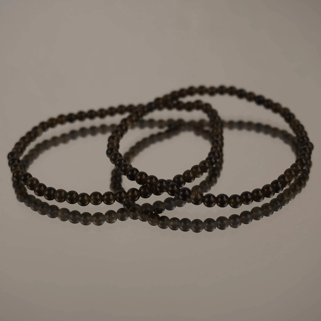 Goldener Obsidian Kugelarmband auf spiegelnder Fläche mit eleganter Reflexion