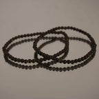 Goldener Obsidian Kugelarmband auf spiegelnder Fläche mit eleganter Reflexion