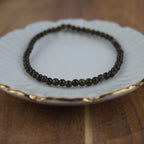 Goldener Obsidian Kugelarmband auf weißem Schmuckteller mit feinem Goldrand