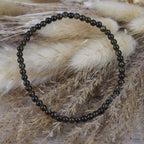 Goldenes Obsidian Kugelarmband auf beigen Trockenblumen im natürlichen Boho-Stil