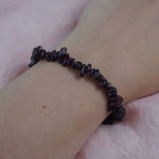 Granat Splitterarmband am Handgelenk vor zartrosa Hintergrund