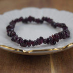 Granat Splitterarmband auf weißem Teller mit feinem Goldrand