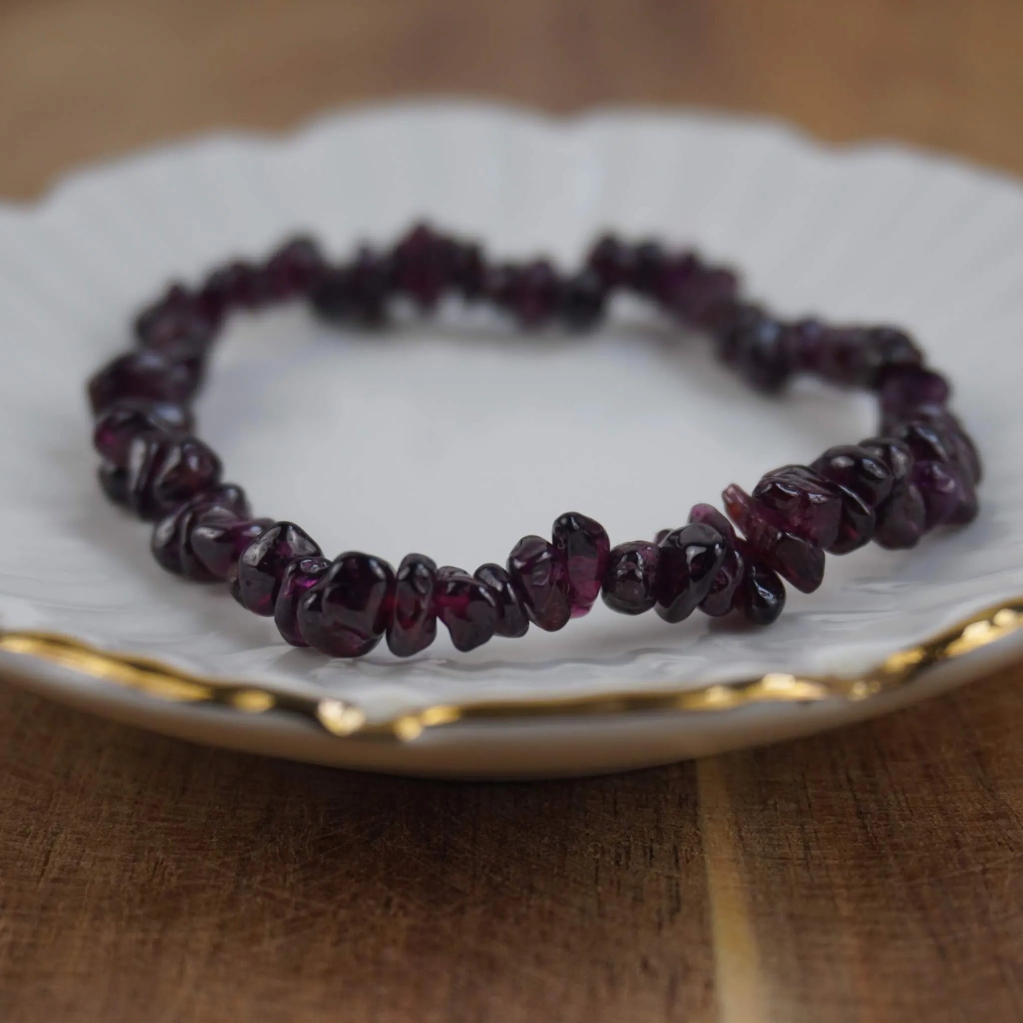 Granat Splitterarmband auf weißem Teller mit feinem Goldrand