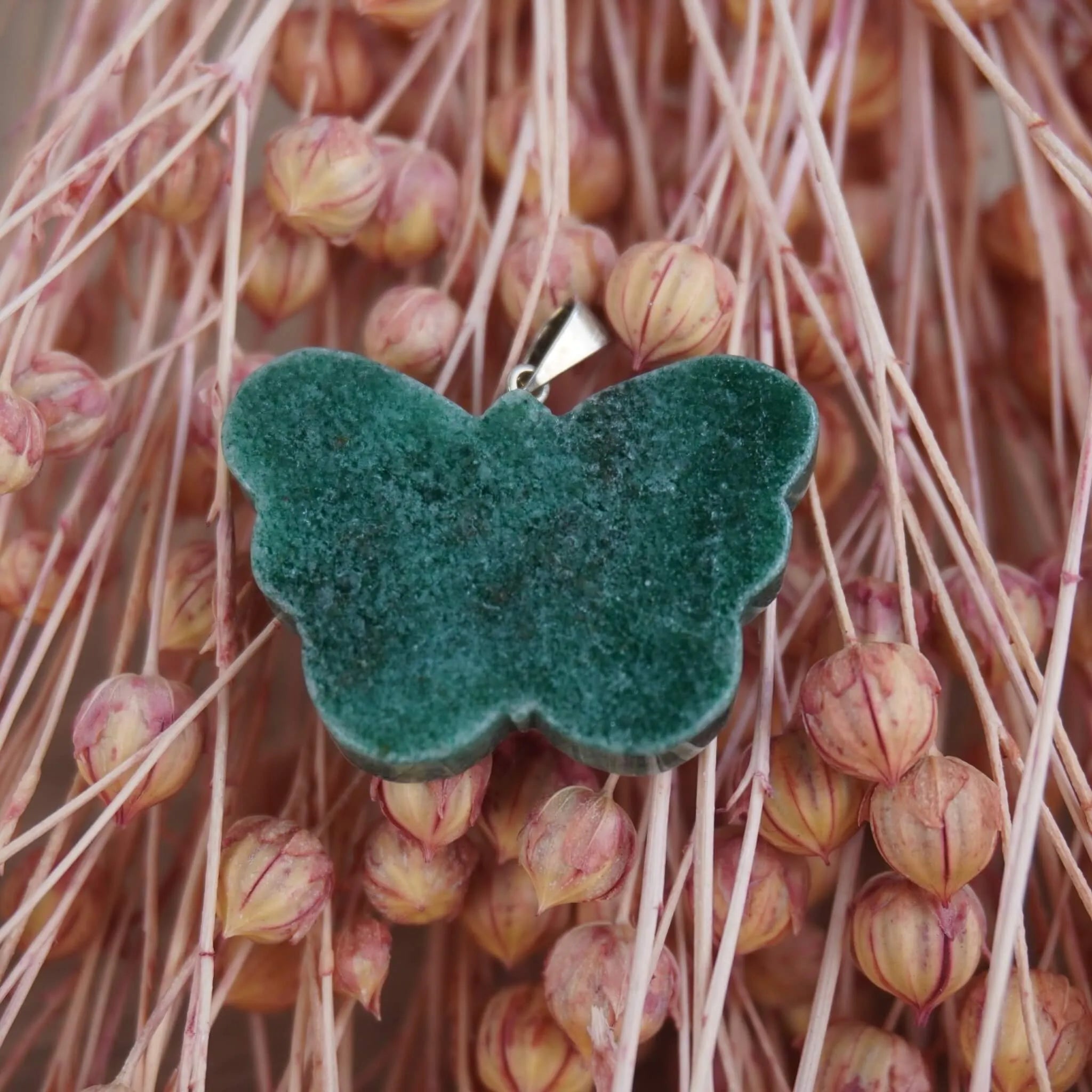 Grüner Aventurin Schmetterling Kettenanhänger vor rosa Trockenblumen