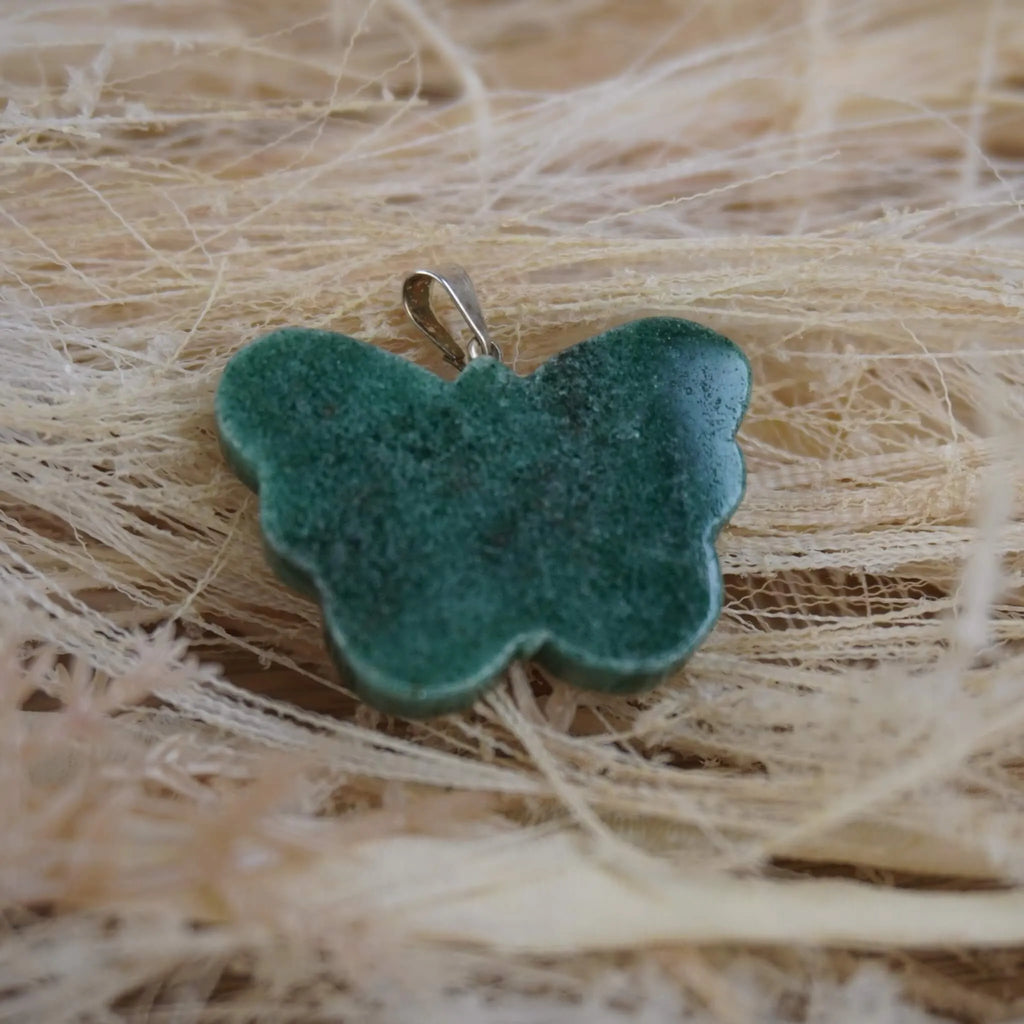 Grüner Aventurin Schmetterling Kettenanhänger auf hellen Naturfasern liegend