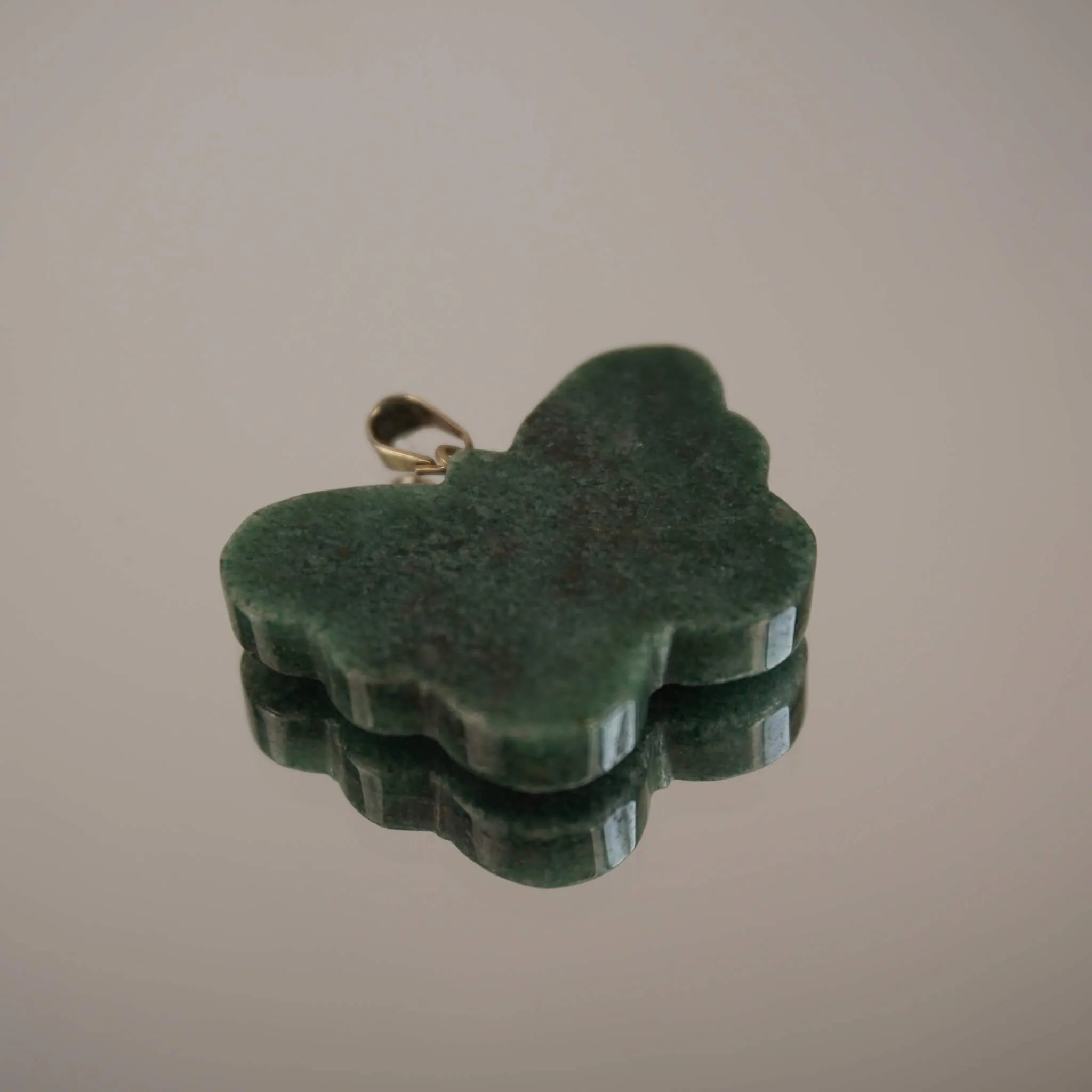 Grüner Aventurin Schmetterling Kettenanhänger mit silberner Öse und Spiegelung auf glänzender Fläche