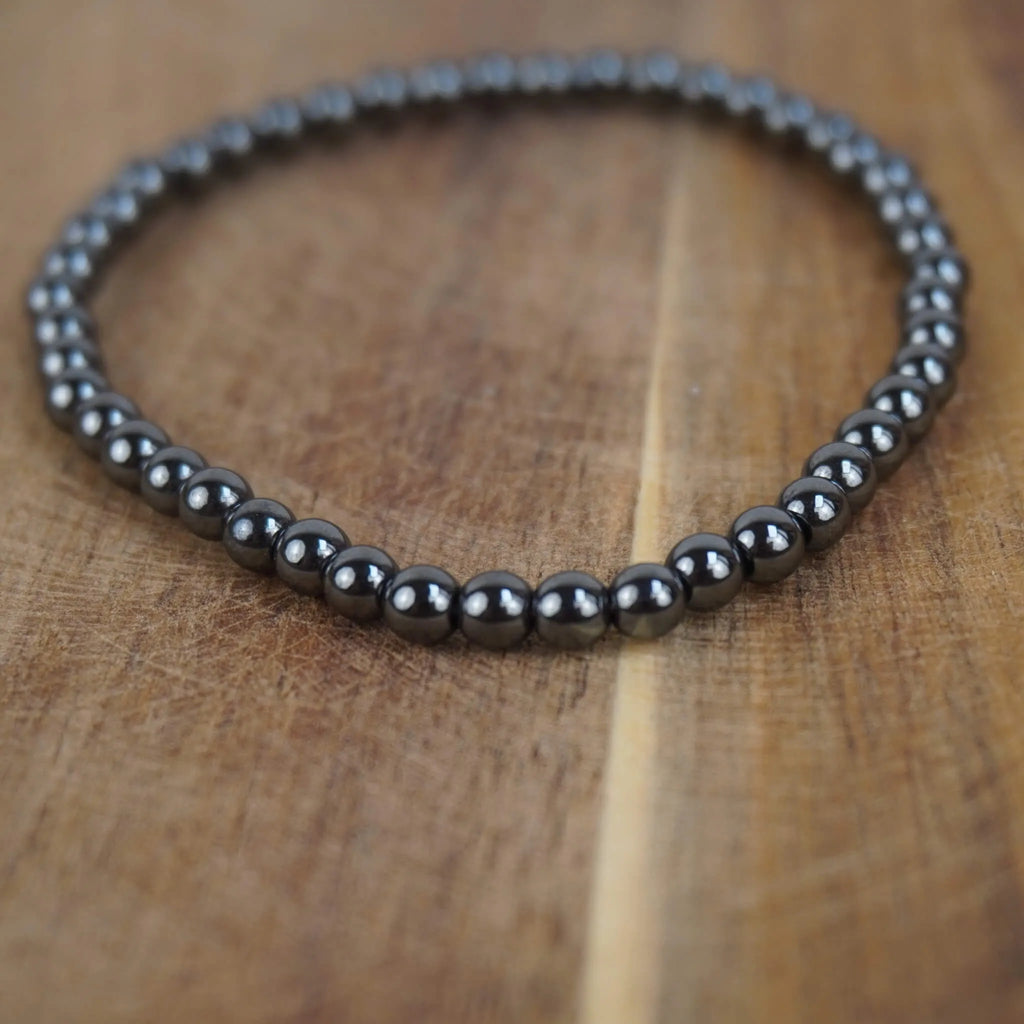 Hämatit Kugelarmband auf warmem Holzuntergrund in Nahaufnahme