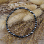 Hämatit Kugelarmband vor beigen Trockenblumen im natürlichen Boho-Stil