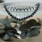 Hämatit Kugelarmband an Glas-Schale mit dunklen Eukalyptusblättern arrangiert