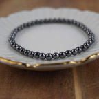 Hämatit Kugelarmband auf weißem Teller mit elegantem Goldrand