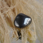 Hämatit Trommelstein mit Glanz auf hellen Naturfasern arrangiert