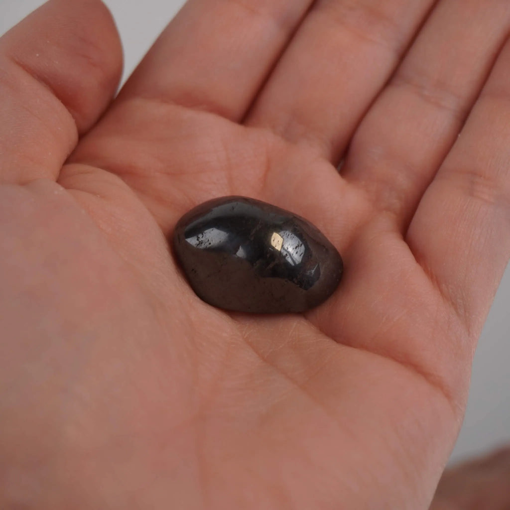 Hämatit Trommelstein in einer geöffneten Hand gehalten